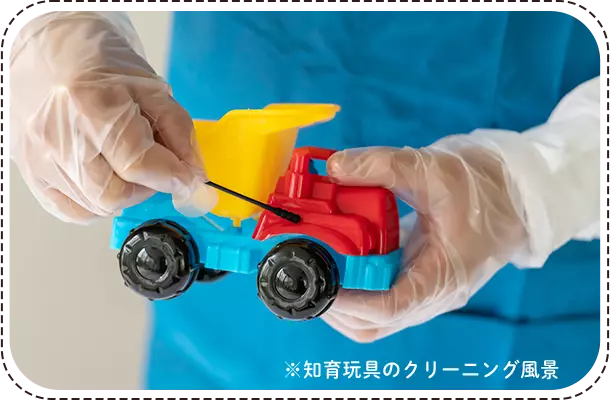 スタッフが手袋を着けておもちゃのトラックを清掃する様子