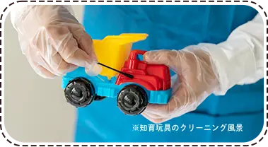 スタッフが手袋を着けておもちゃのトラックを清掃する様子