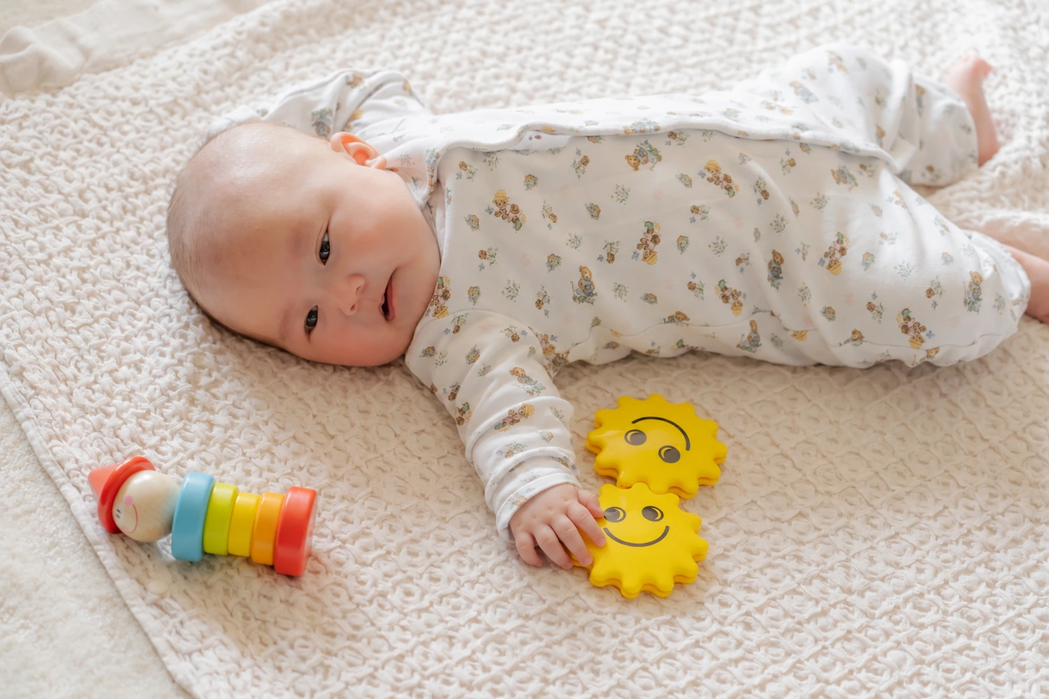 黄色いおもちゃの縁に指先をのせ、実際にふれているお子さまの小さな手