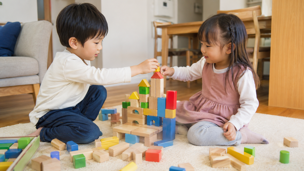 男の子と女の子が一緒に積み木やブロックで遊んでいる自然な室内の写真。性別に関係なく同じ玩具で楽しんでいる様子を示すイメージ