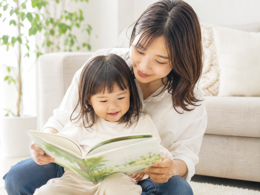 親子が一緒に絵本の読み聞かせをしているやさしい雰囲気のイメージ写真