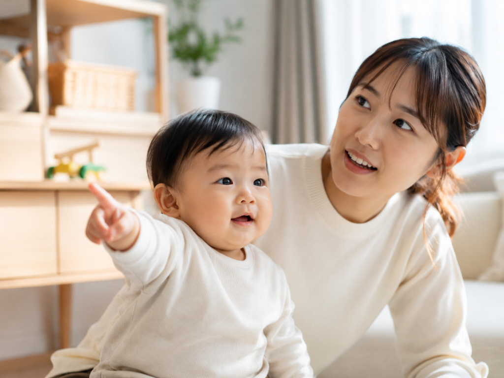 赤ちゃんが指差しをして親が同じ方向を見ている場面の写真