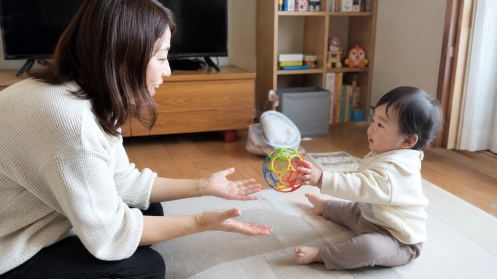 保護者と赤ちゃんがオーボールを転がして受け渡ししている場面