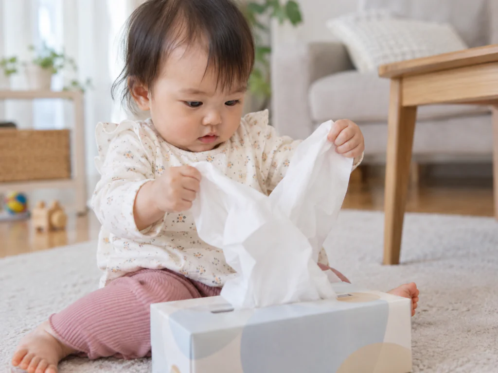 赤ちゃんがティッシュを両手でつまんで引き出している様子
